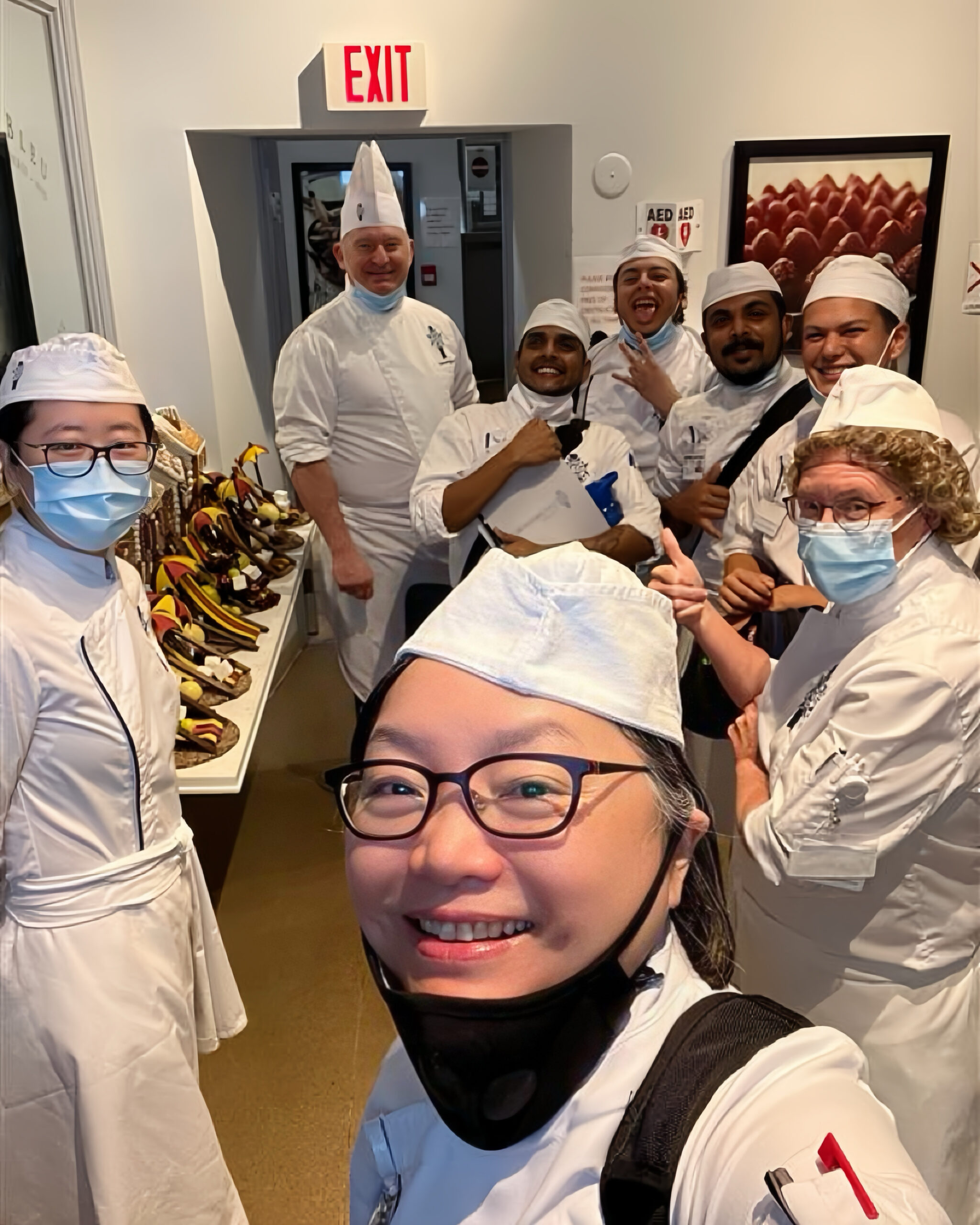 A class of Cordon Bleu Ottawa students posing for a photo, giving the thumbs up, wearing their chef's uniforms.