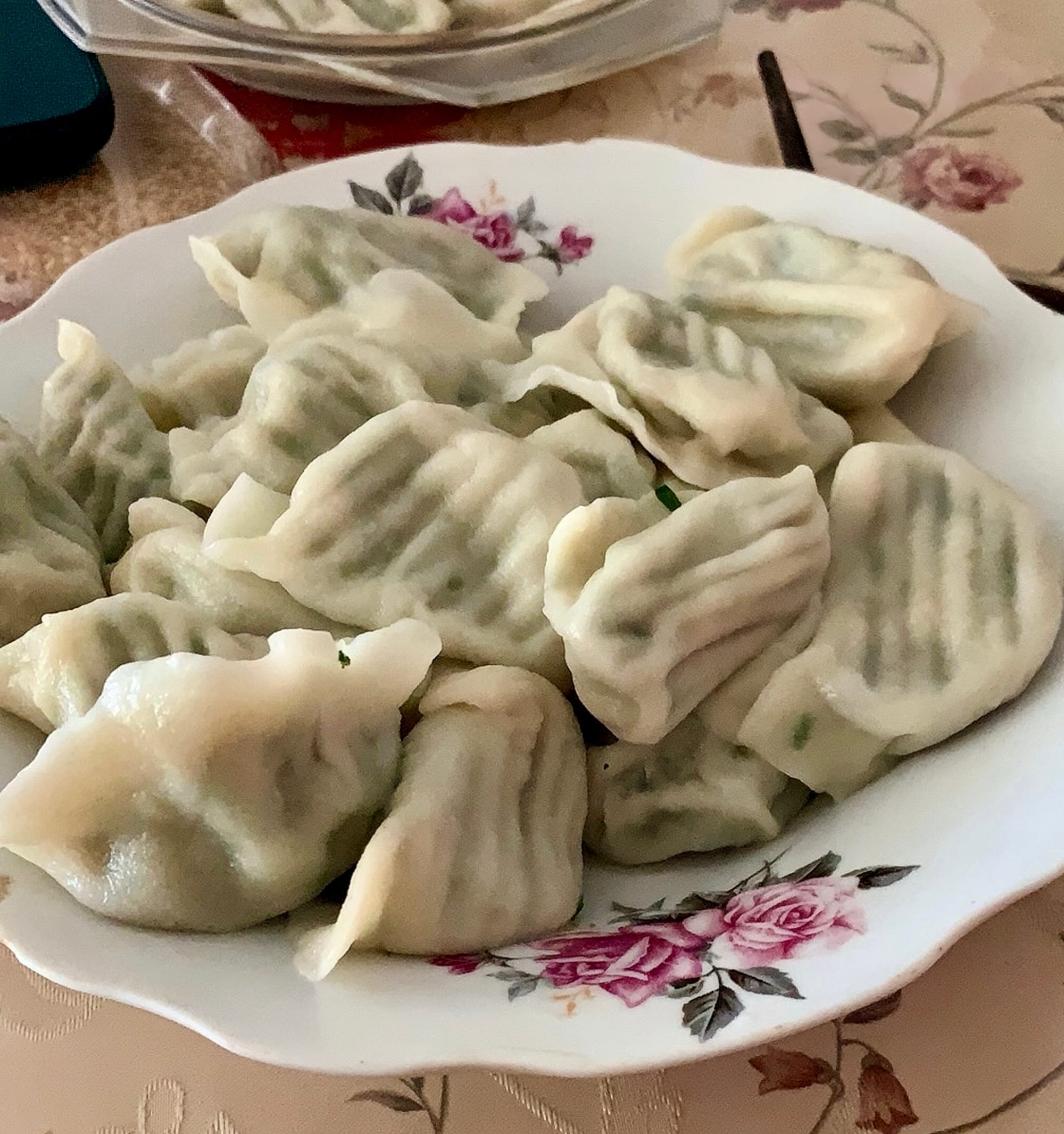 A decorated white plate filled with steamed dumplings.