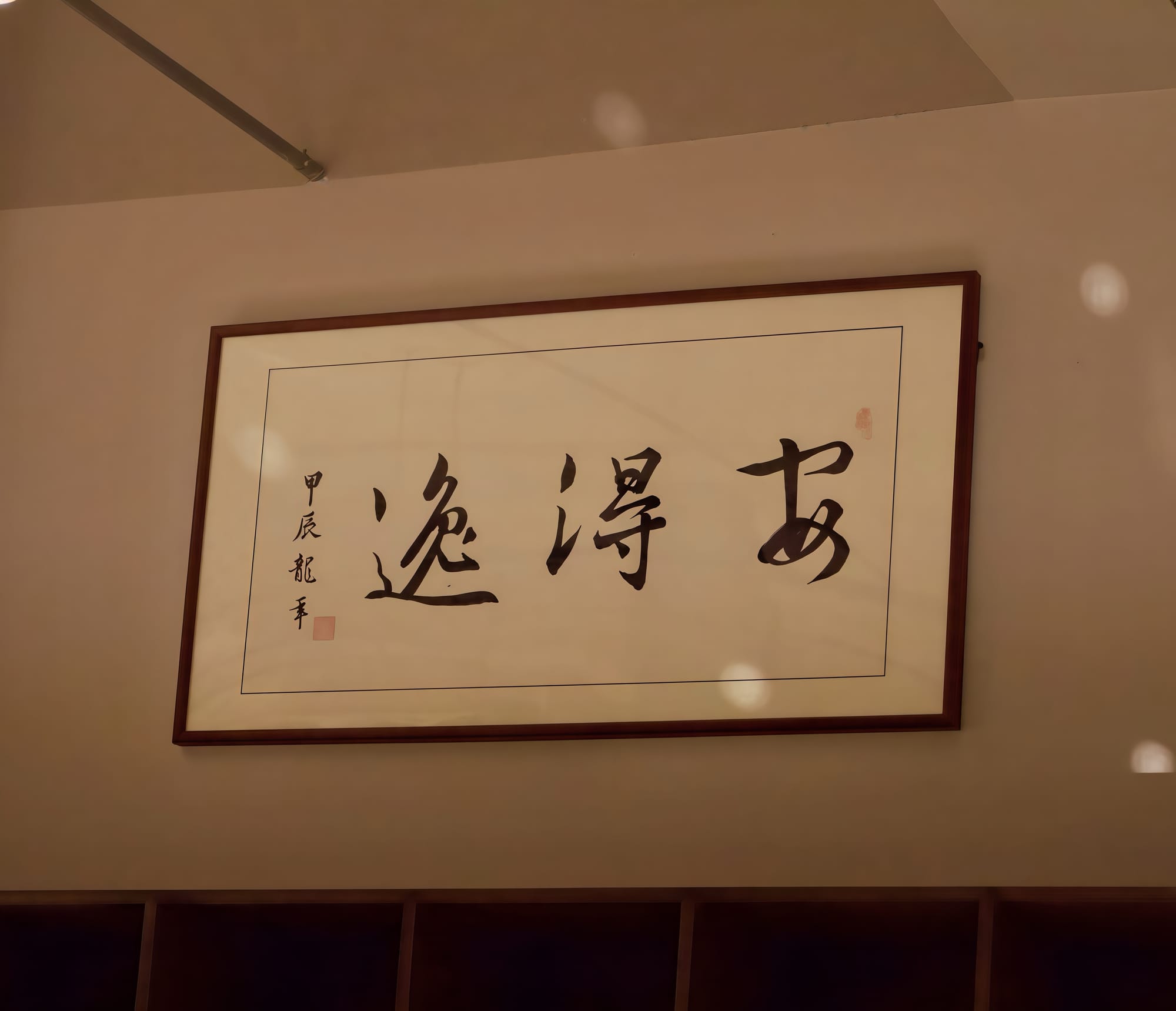 A white scroll with black ink Chinese characters in calligraphy says An De Yi.