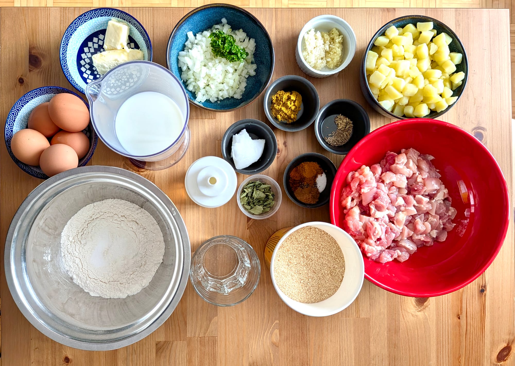 The array of ingredients all portioned in dishes on a cutting board for the dish: chicken rolls.
