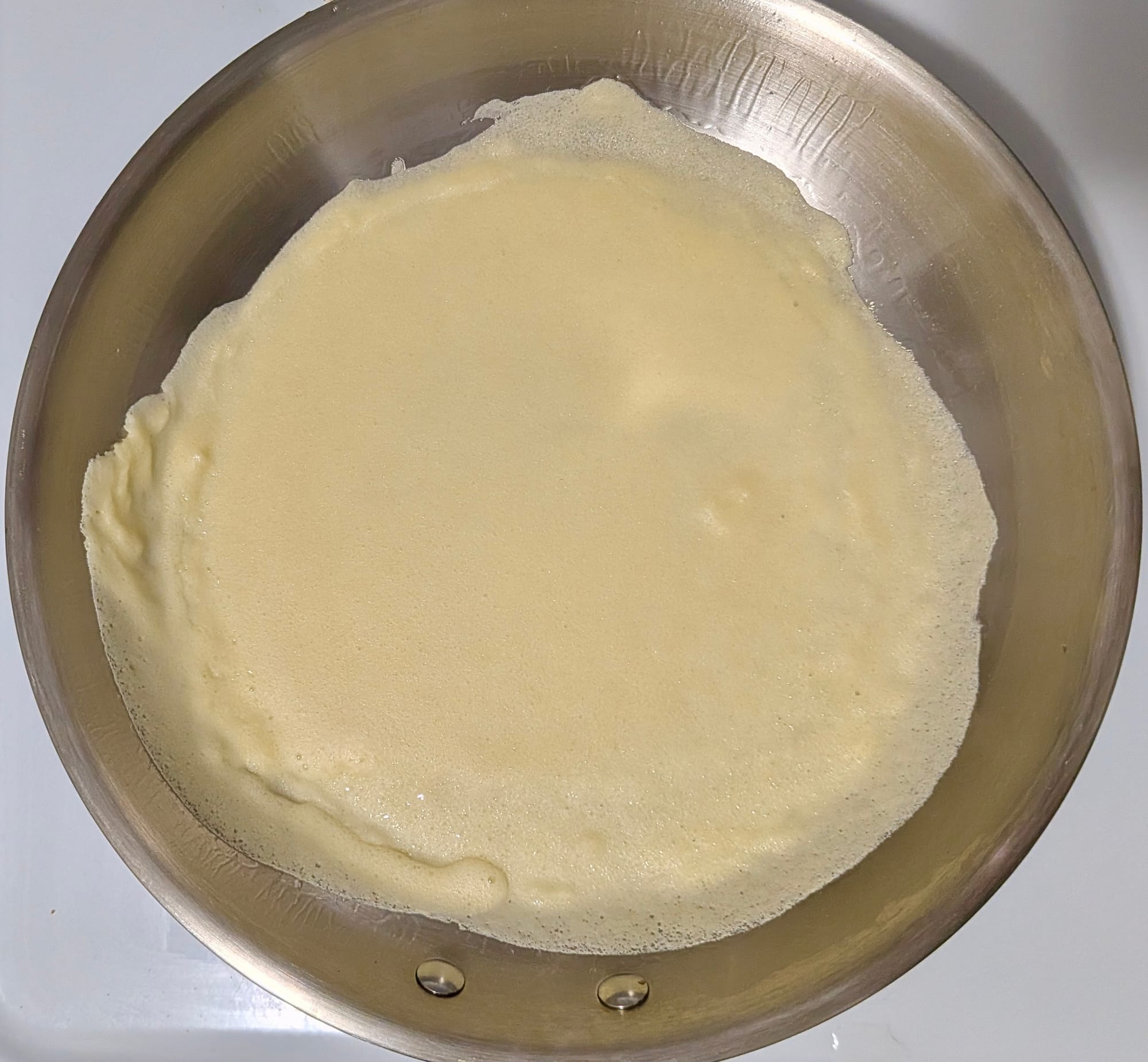 Crepe batter in a pan being cooked.