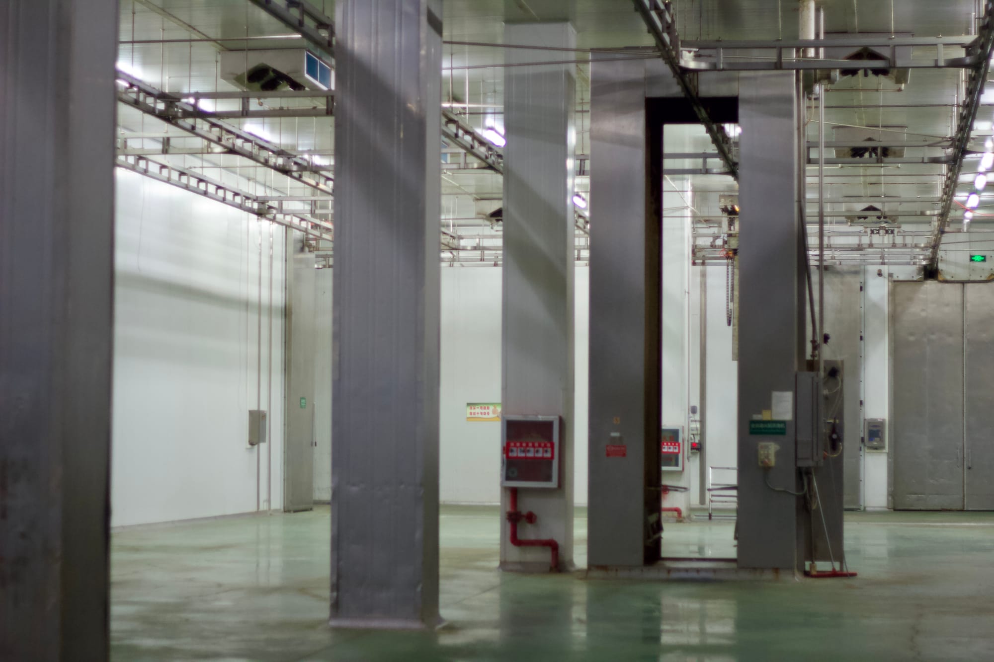 An empty warehouse production floor with large pillars scattered throughout the middle.