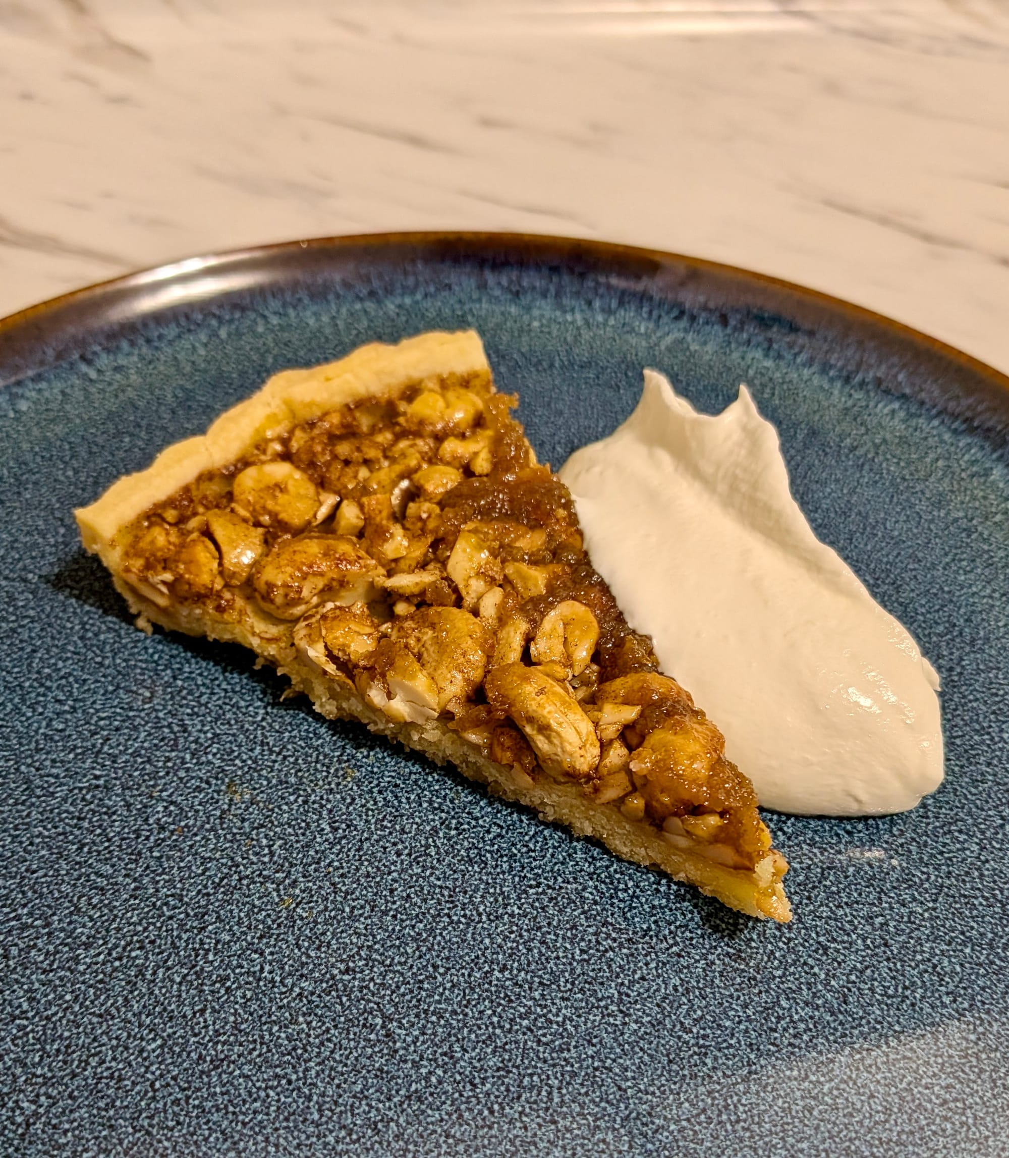 Cashew Nut and Kithul Treacle Tart with Chantilly Cream on a plate