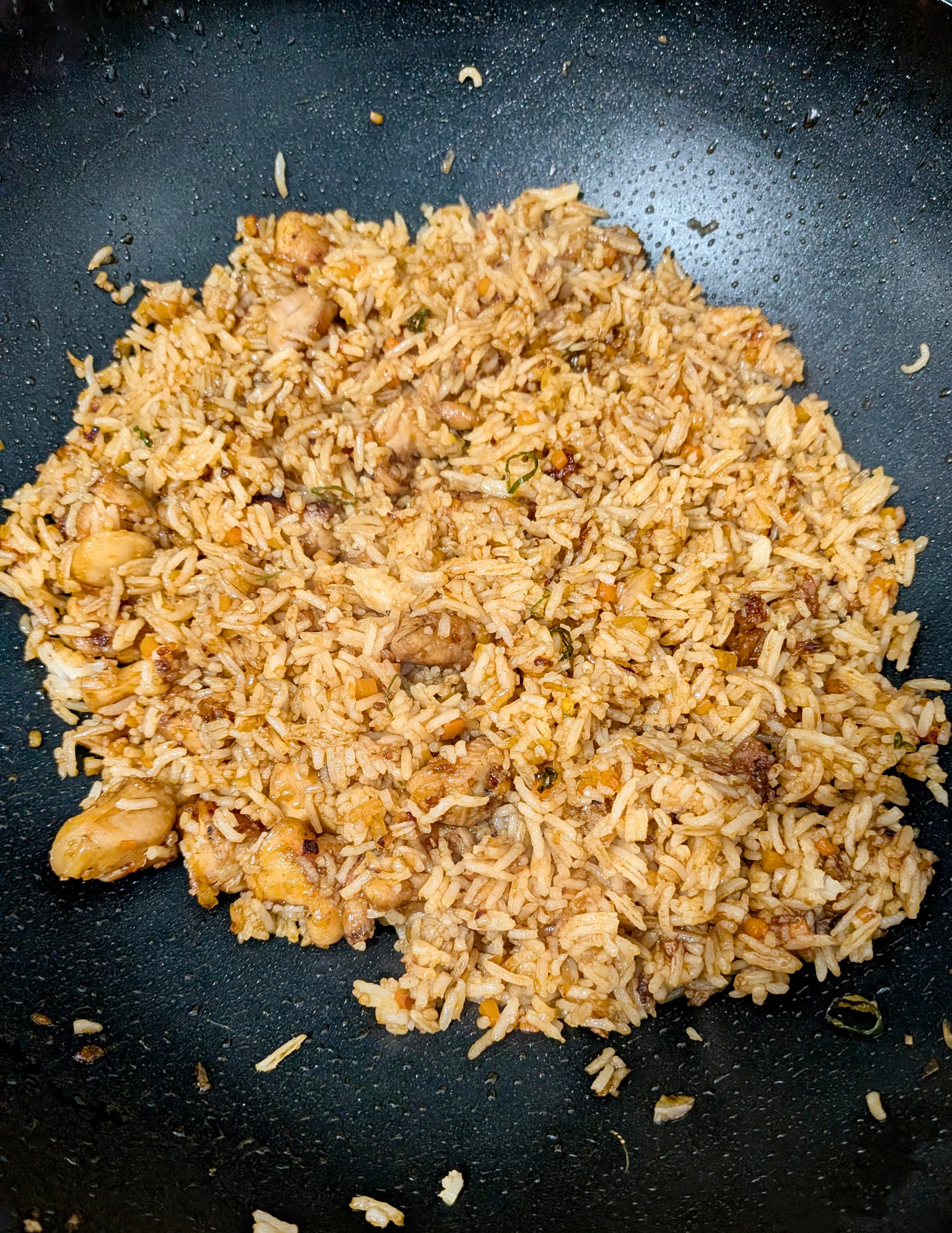 Nasi goreng being fried in a pan, looks like a typical fried rice.
