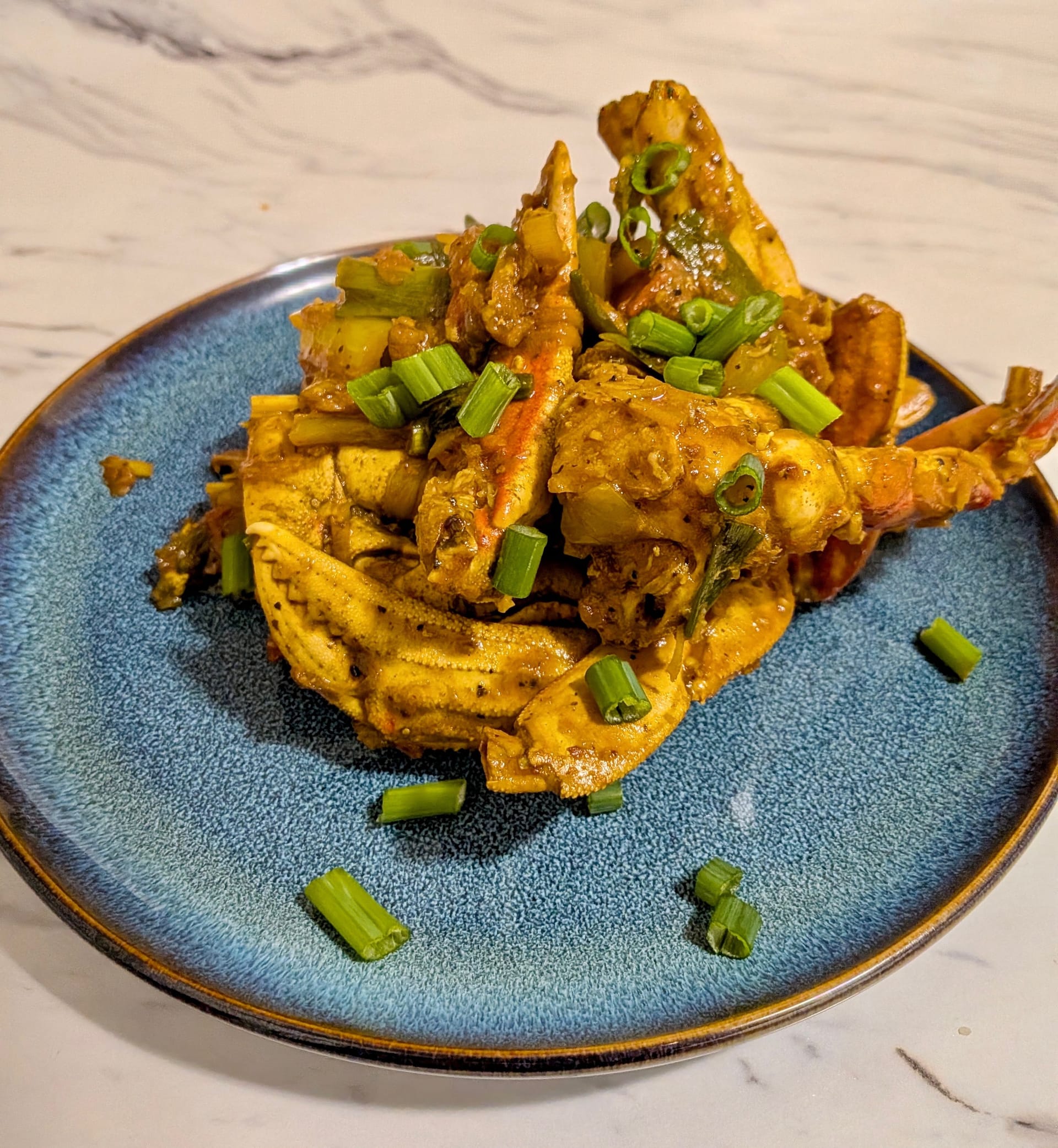 Plated Deviled Crab - a yellow-ish brown crab with green onions to garnish.