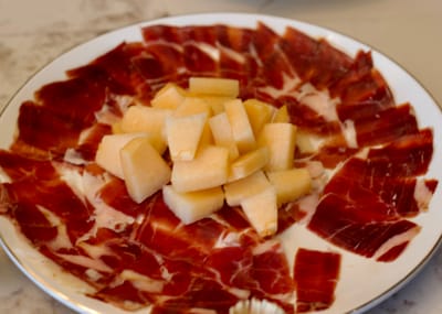 Jinhua ham surrounds cantaloupe melon on a plate. 